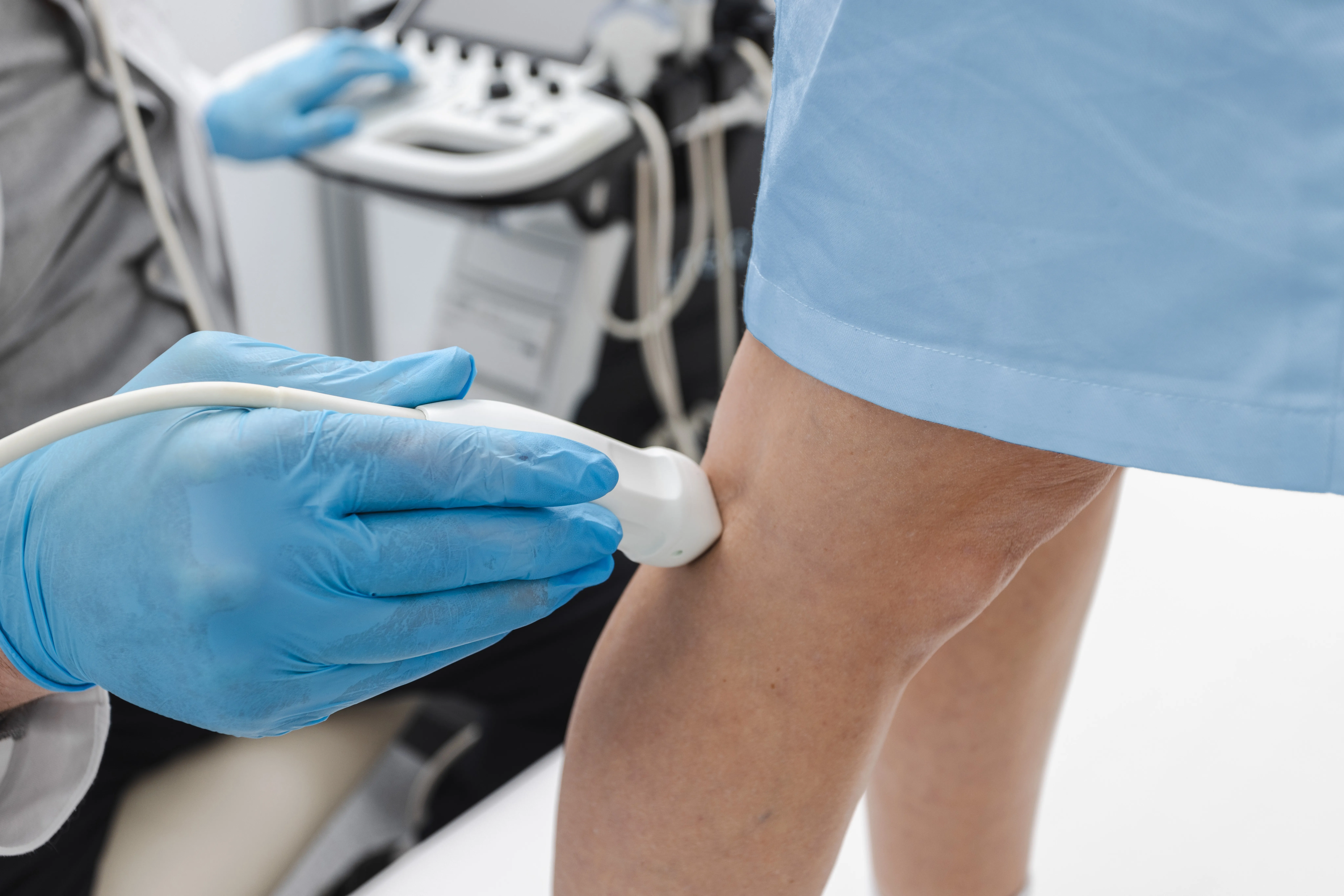 Médico realizando um ultrassom de membro inferior em um paciente